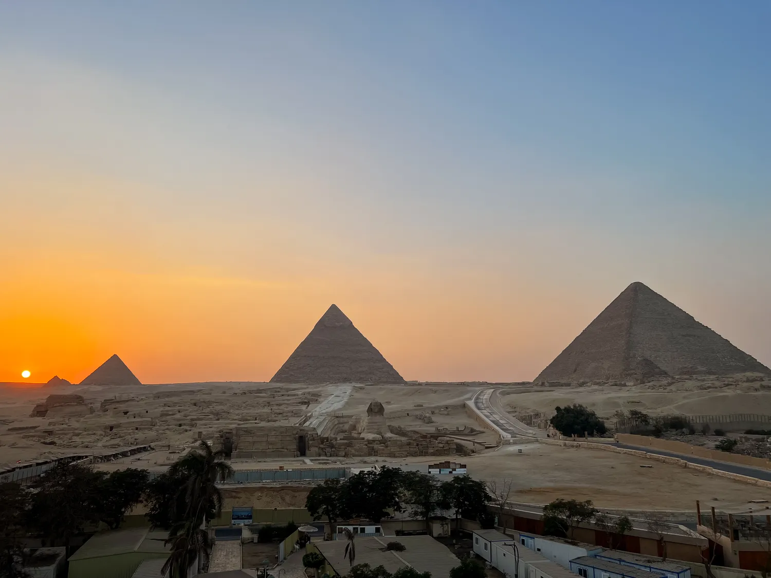 Sunset over the three pyramids of Giza and the plateau below